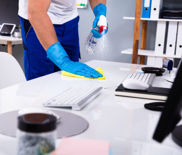 Janitor cleaning white desk in modern office