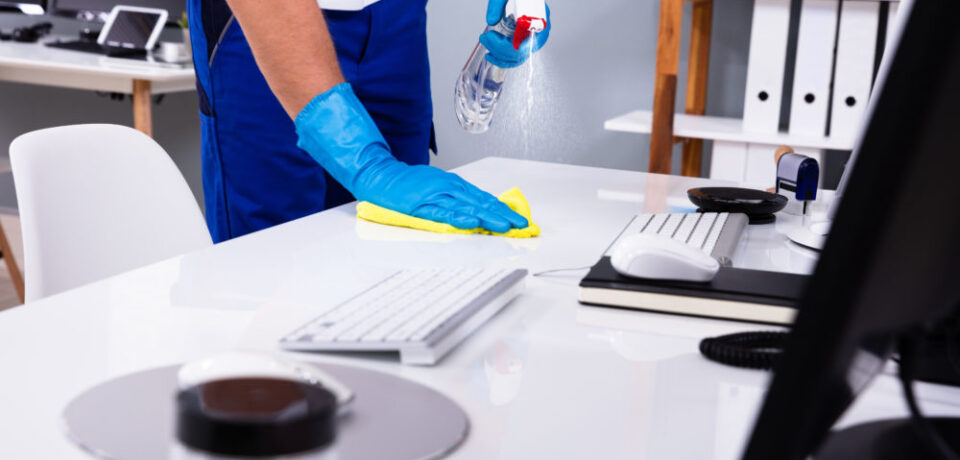 Janitor cleaning white desk in modern office