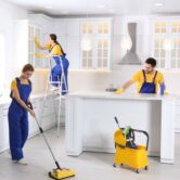 Team of professional janitors cleaning modern kitchen