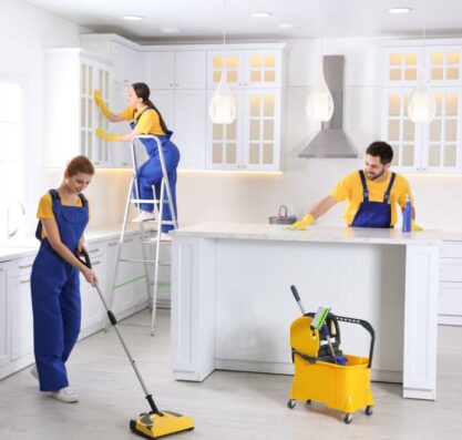 Team of professional janitors cleaning modern kitchen